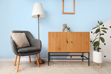 Interior of modern room with comfortable armchair, commode and houseplants near color wall