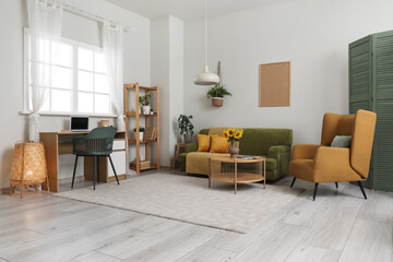 Interior of living room with workplace, sofa and armchair