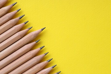 Many pencils on yellow background, top view. Space for text