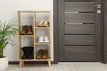 Shoe storage. Shelving unit with different footwear and houseplant indoors