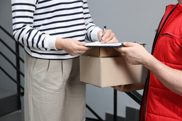 Courier with boxes and receiver signing for delivered parcels indoors, closeup