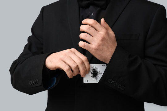 Young man taking ace card from sleeve on grey background, closeup