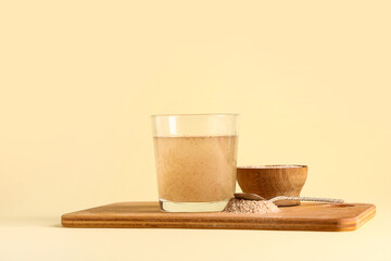 Glass of water with psyllium husk on beige background