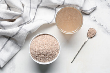 Glass of water with psyllium husk on light background