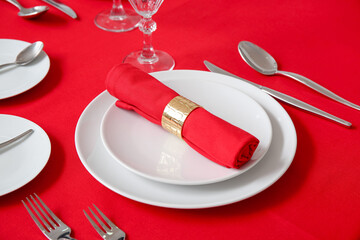 Minimalist setting with red tablecloth, plates, napkin and cutlery on table