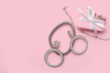 Beautiful silver bracelets with earrings and gift box on pink background