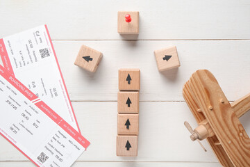 Cubes with tickets and toy airplane on white wooden background. Itinerary concept