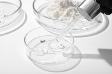Female scientist's hands holding pipette and Petri dishes with samples on white background