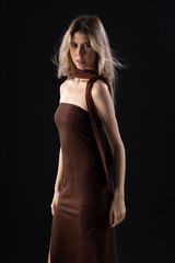 Naklejka premium Young blonde woman wearing a luxurious dress on a black background