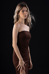 Young blonde woman wearing a luxurious dress on a black background