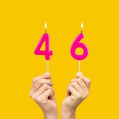 Birthday number 46 - Hands holding fuchsia colored candles