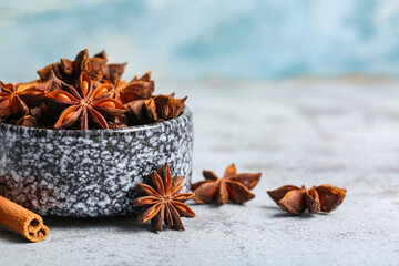 Bowl with anise stars and cinnamon on grey table
