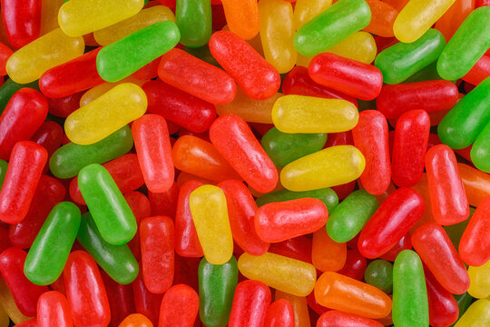 Vibrant assortment of colorful jelly bean-shaped candy in red, yellow, green, and orange tones.