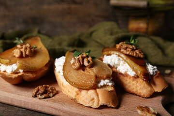 Board of pear bruschetta with ricotta cheese, walnuts and mint on wooden background, closeup