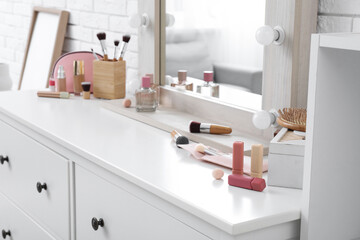 Chest of drawers with cosmetics and mirror in stylish makeup room, closeup