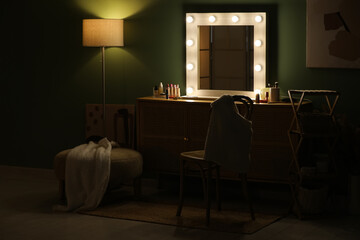 Interior of dark makeup room with glowing mirror, wooden cabinet and cosmetics