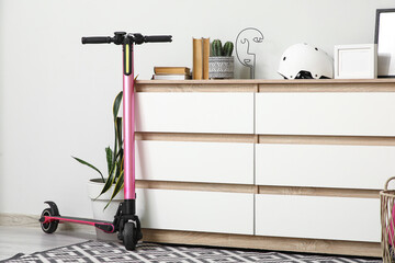 Interior of living room with electric scooter, commode and houseplant