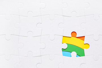 Rainbow visible through white puzzle pieces, closeup. Autistic disorder concept
