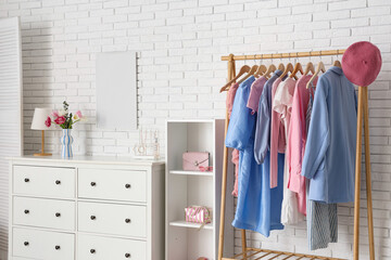 Interior of light dressing room with clothes rack, chest of drawers and folding screen
