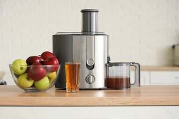Modern juicer with fresh apples on table in kitchen