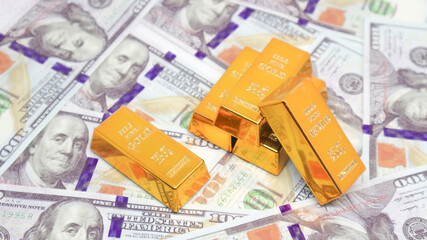 gold bullion glistens on top of a stack of US dollar bills. gold investment concept