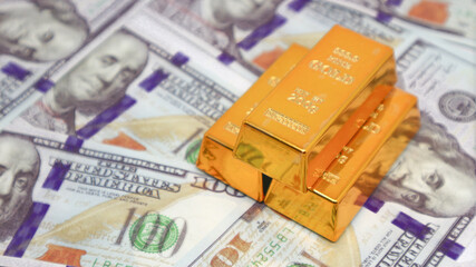 gold bullion glistens on top of a stack of US dollar bills. gold investment concept