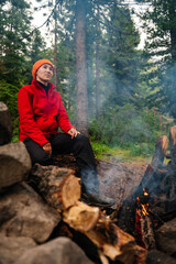 Naklejka premium A girl sits by a campfire in the forest