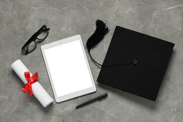 Graduation hat, tablet computer, glasses and diploma on grey background, top view