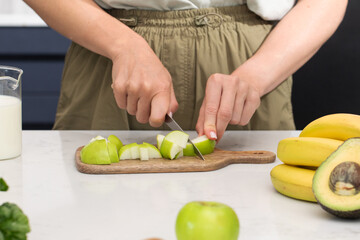 Healthy cooking with fresh fruit, cutting green apples on a cutting board