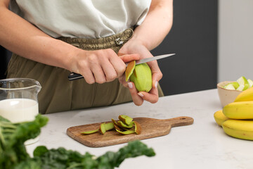 Preparing fresh kiwi slices for a healthy smoothie in a modern kitchen setting