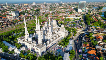 Sheikh Zayed Grand Mosque in Solo glows under the soft morning light, its white domes and elegant minarets standing tall in a peaceful, serene landscape.