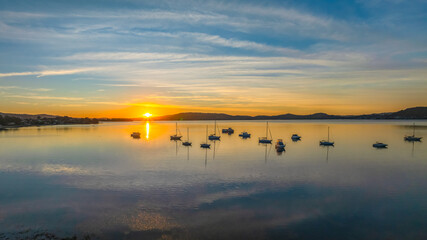 Naklejka premium Sunrise with high cloud, boats and reflections over the water