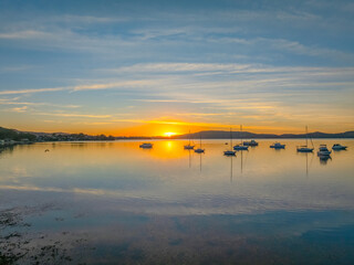 Fototapeta premium Sunrise with high cloud, boats and reflections over the water