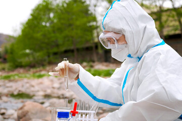 Environmental Scientist Conducting Field Research in Protective Gear by a Stream