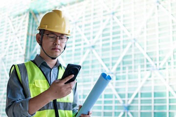 Asian male engineer  using smart phone  at the construction site