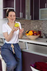 Obraz premium Beautiful active female standing with happy face, enjoying eating fruits, healthy foods for health care wellness to lose weight in house. Diet concept. Fitness and healthy food