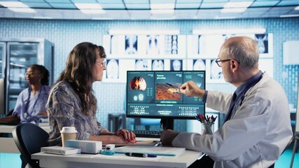 Male oncology specialist reviewing a radiology scan with elderly woman patient, explaining risk factors and preventive options for cancer diagnosis and treatment. Immunotherapy.