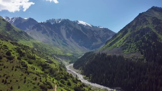 This drone footage showcases the stunning scenery of Ala Archa National Park, with alpine trees in the valley and mountains partially covered by clouds.