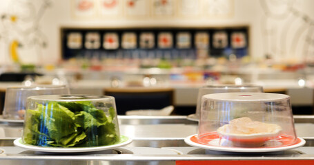 Plates of fresh sushi rotating on a conveyor belt in a vibrant restaurant, covered with transparent domes, waiting for customers to enjoy a delightful dining experience