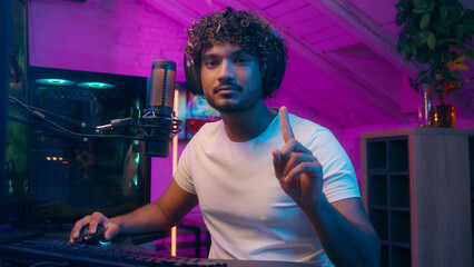 Excited Indian Arabian Latino man shaking finger no influencer playing addict gamer cyber sport...