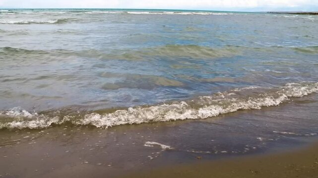 This footage shows a wave gently approaching the sandy shores of Assyk Kul Lake, providing a peaceful and calming natural scene.