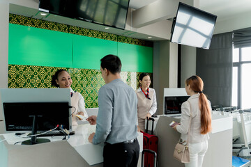 Airline staff assisting passengers at check-in counter with luggage and boarding passes, providing professional customer service at modern international airport
