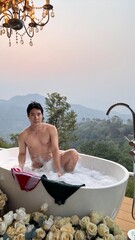 Handsome Man Relaxing in a Bubble Bath with a Stunning Mountain Sunset View