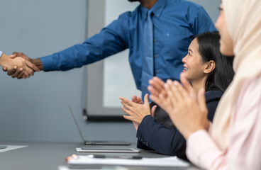 Obraz premium Multiracial team collaborating in modern office, diverse colleagues shaking hands during a business meeting, teamwork success, partnership agreement, professional collaboration multicultural workplace