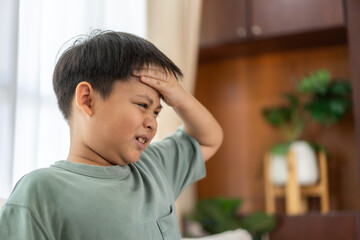 Portrait of sick depressed unhappy child boy touching on head feel suffering head ache pain flu high fever, alzheimer, cancer, stroke disease, cerebral haemorrage, encephalitis, dementia