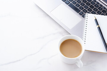 淹れたての美味しいコーヒー、カフェ・ラッテを飲みながら、ノートパソコンでデスクワーク中のイメージ
