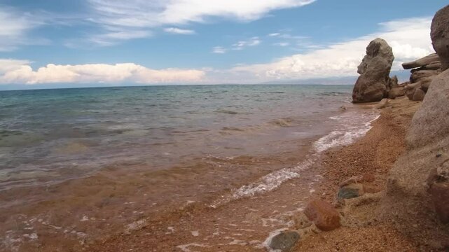 Assyk Kul Lake, with its clear waters and rocky shorelines, offers a tranquil setting surrounded by beautiful natural scenery in Kyrgyzstan, ideal for photography and exploration.