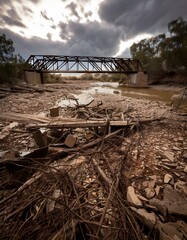 A destroyed bridge symbolizes the severed connections left behind after conflict, set against a moody sky.