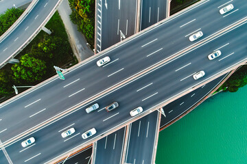 Aerial of vehicles navigate a complex highway system, showcasing overpasses and intersections.