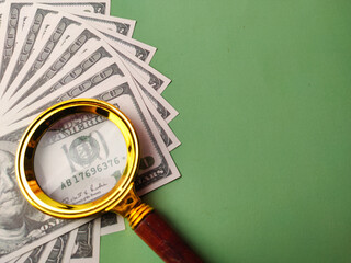 Closeup gold magnifying glass on a one hundred dollars